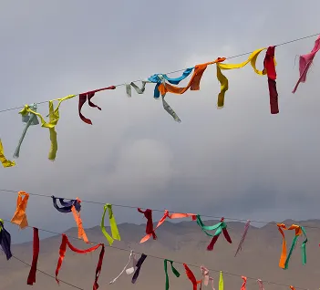 Cintas de colores atadas a un cable, con cerros de fondo