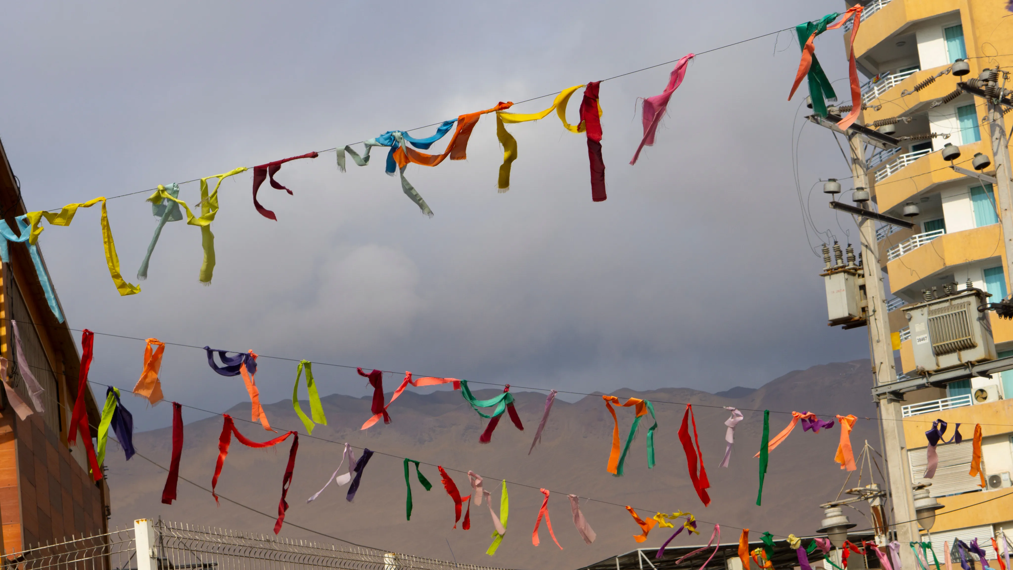 Cintas de colores atadas a un cable, con cerros de fondo