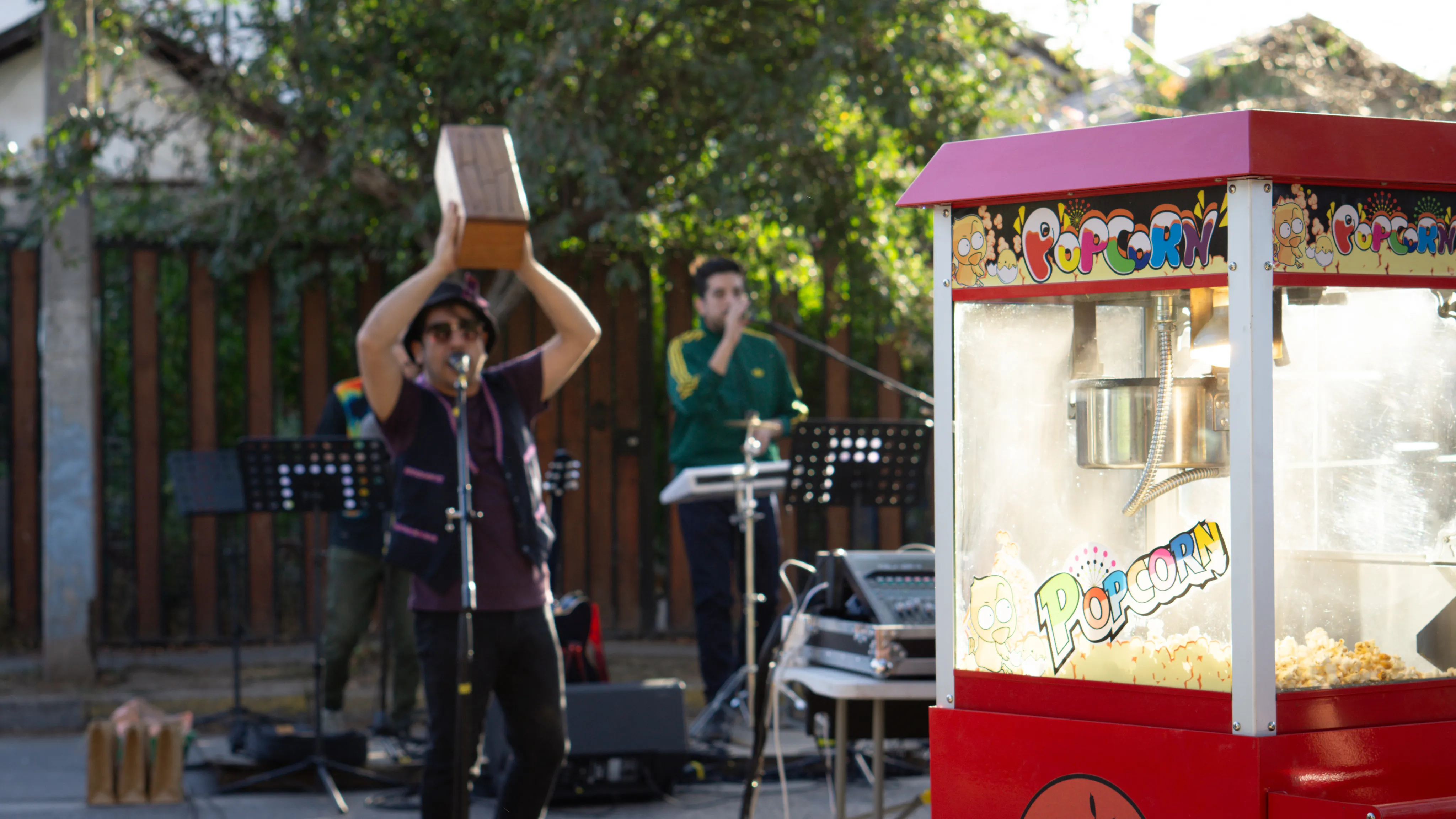 Músicos tocando en la calle junto a un carro de popcorn